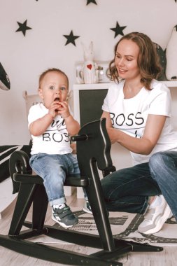 Çocuk odasında annemin yanındaki siyah bir atın oğlu. Kot pantolon ve tişört. Mutluluk. Oyun