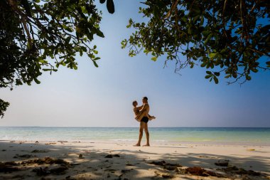 Young tourist couple hugging on secret beach on Pangkor island in Malaysia. Beautiful seascape and harbor taken in south east Asia. clipart