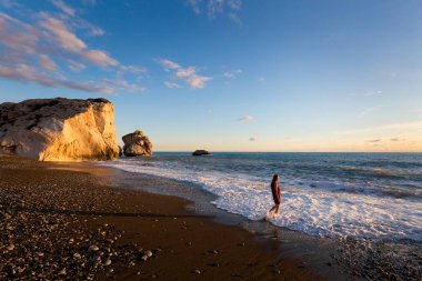 Genç kafkas kadın turist susnet sırasında taş sahilde güzel Afrodit Kayalıkları üzerinde. Kıbrıs Adası'nda alınan manzara.