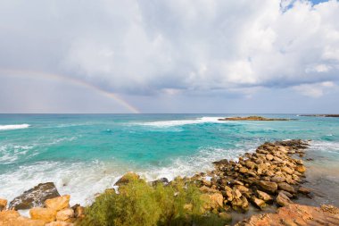 Güzel Cape Greco Protaras incir plaj sahil rock bulutlu hava sırasında dolu. Kıbrıs Adası'nda alınan gökkuşağı ile manzara.