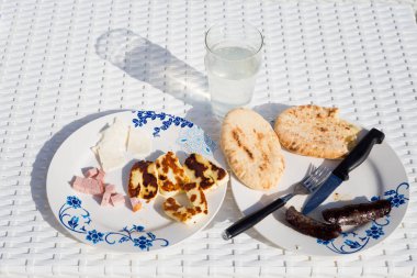 Dizi Hellim, jambon kahvaltı, sosis ve pide ekmek Voroklini yerel restoranda şarap. Kıbrıs adasında geleneksel Kıbrıs yemekleri.