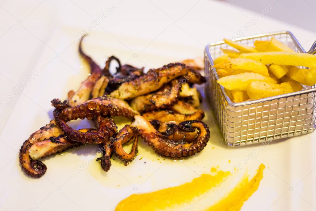 Grilled octopus served with chips in local restaurant in Larnaca. Traditional cypriot food on Cyprus island.