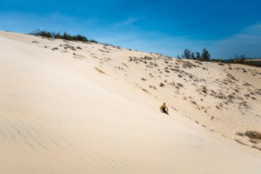 Genç yakışıklı adam, Vietnam 'ın Phan Tiet bölgesinde, La Gi' deki beyaz kum tepelerinde eğleniyor. Mui Ne 'nin güneyinde mavi gökyüzü olan manzara.