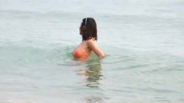 Denizde oynayan bikini giyen bir kadın.