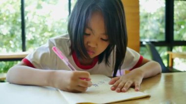 Oturma odasında oturan bir kız resim çiziyor.