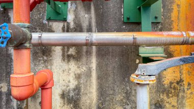 Renkli yangın söndürme boruları ve kontrol ekipmanları, güvenlik, yangın önleme, işlevsellik ve yönetmeliklere uymayı sembolize eden endüstriyel bir fabrikaya kurulmuştur..