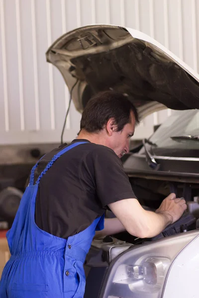 Technician working in the auto service and repairing a car