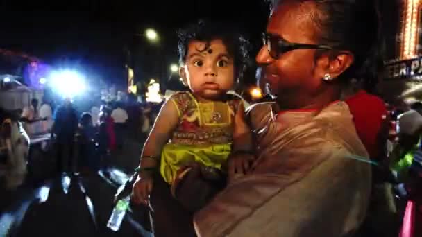 Un enfant indien est câlin par les parents à la rue LED colorée pendant Thaipusam. — Video