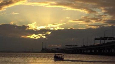 Penang Köprüsü 'nde zaman ayarlı güneş ışığı. Balıkçı teknesi hareket.