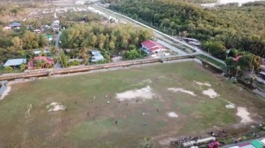 Yerel Malaylılar Kampung 'daki yeşil alanda futbol oynuyorlar.