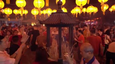 İbadet eden kişi, elinde joss çubuğuyla tapınakta dua eder..