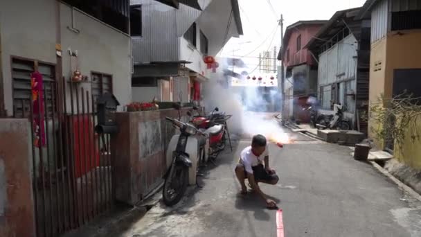 Un hombre enciende las galletas de fuego en la calle durante la celebración del año nuevo chino — Vídeos de Stock