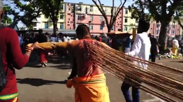 Vue de dos dévots hindous perçage du corps tiré par un ami marcher dans la rue. — Video