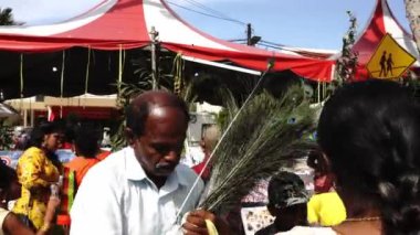 Bir kadın Thaipusam 'da satıcısından tavus kuşu tüyü alır..
