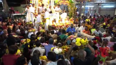 Çiçek ve meyve sunan fanatikler gümüş at arabasında dua ediyorlar..