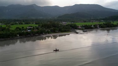 Dağın yakınındaki suda bir tekne var. Su bulanık ve tekne de suyun tam ortasındadır. Gökyüzü görüntüsü Yan, Kedah