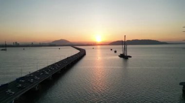 Gelugor, Penang, Malezya - 28 Şubat 2024: Penang Köprüsü, arka planda günbatımı. Köprüde arabalar var.