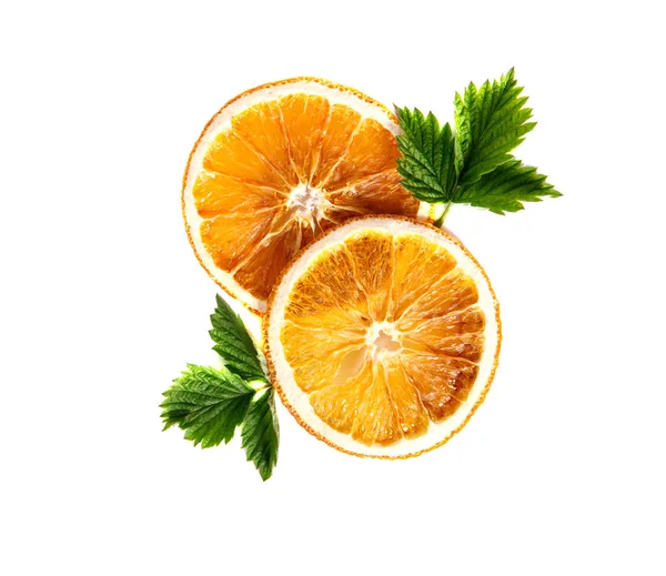 Getrocknete Orangenscheiben mit grünen Blättern auf einem isolierten weißen — Stockfoto