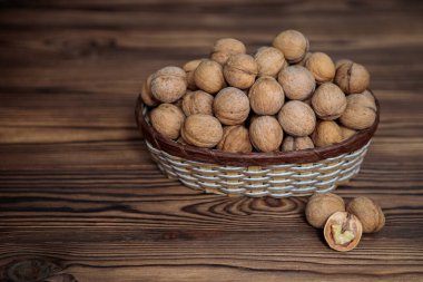 Ahşap bir arka planda içi ceviz dolu bir sepet. Doğal, sağlıklı ürün. Metin için boşluk.