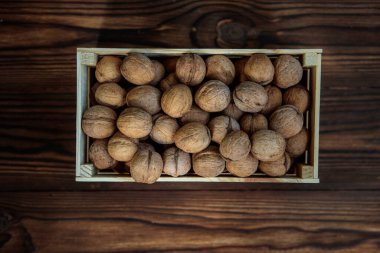 Ahşap arka planda içi ceviz dolu bir kutu. Yukarıdan bak. Doğal, sağlıklı ürün. Metin için boşluk.