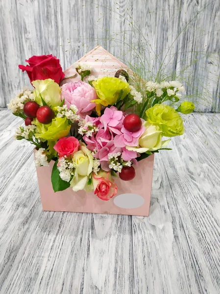 Flowers and fruits in the envelope - a beautiful idea for a romantic Gift. Flower composition close-up on a wooden vintage background. Work in a flower shop