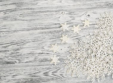 Düz beyaz ahşap masa üzerinde dekoratif kar taneleri yatırın. Fikir Noel arka planı için