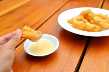 Derin yağda kızartılmış hamur sopa ahşap arka plan üzerinde şekerli yoğunlaştırılmış süt ile.