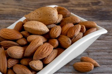 eski ahşap masa üzerinde kızarmış kurutulmuş badem kase