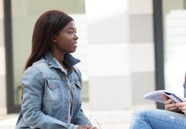 Genç siyahi kız kitapla oturuyor.