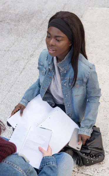 Genç siyahi kız kitapla oturuyor.