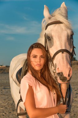 Gün batımında sahilde beyaz at ile genç güzel kız