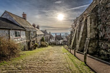 Famous Gold Hill in Shaftesbury with sun in sky taken in Shaftebury, Dorset, UK on 3 January 2017 clipart