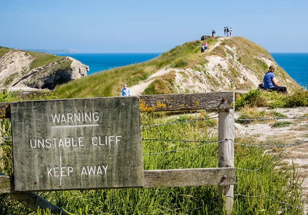 Tourists ignoring danger unstable cliff sign at Lulworth Cove, Dorset, UK on 11 July 2013