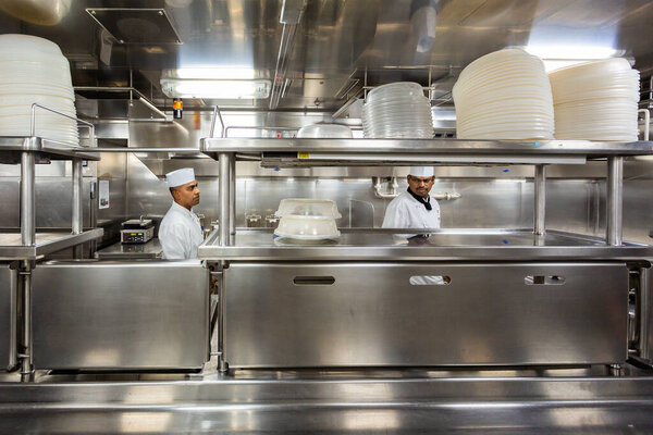 Behind the scenes view of food preparation in the kitchen, galley on board a large cruise ship at Sea in Queen Victoria in the Baltic Sea on 24 July 2019