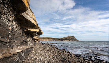 Kimmeridge Körfezi 'nin kayalık kıyı şeridi ve şist ve kireçtaşı uçurumları ile Kimmeridge, Purbeck Adası, Dorset, İngiltere' de 26 Ağustos 2020 'de arka planda The Clavell Tower var.