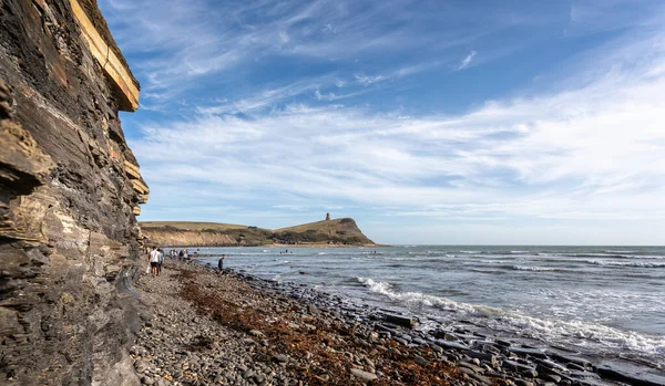 Kimmeridge Körfezi, kayalık kıyı şeridi ve fosil avcılarıyla, The Clavell Tower arka planda Kimmeridge, Purbeck Adası, Dorset, İngiltere 'de 26 Ağustos 2020 tarihinde