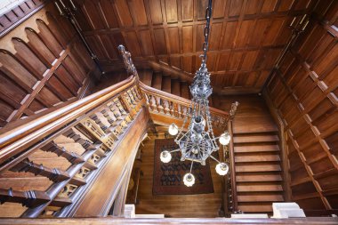 7 Eylül 2025 'te Knightshayes Court, Tiverton, Devon, İngiltere' deki büyük ahşap merdivenlere ve avizeye bakıyor.