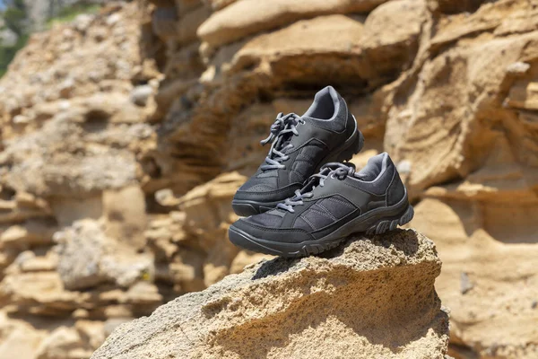 Hiking shoes on rocks, cliffs in the background