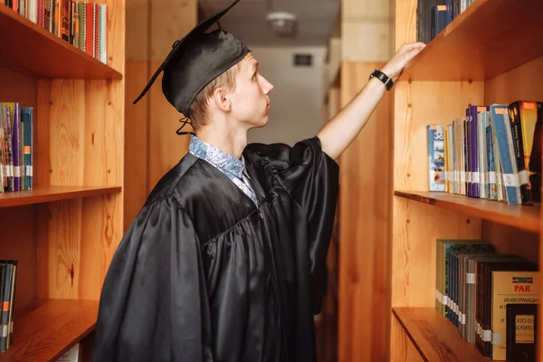 Erfolgreicher Absolvent Akademischer Kleidung Der Bibliothek Stehend Bücher Auswählend Kann — Stockfoto