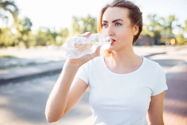 Young sports girl, drinking water from the bottle, after a hard workout, can be used for advertising