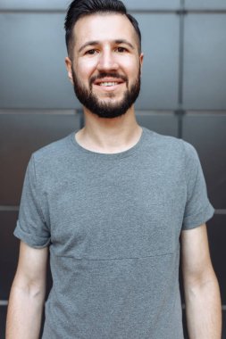 Güzel şık biri siyah duvar arka plan üzerinde bekleyen bir gri boş t-shirt giymiş hipster portresi.