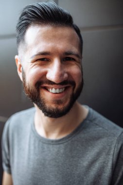 Güzel şık biri siyah duvar arka plan üzerinde bekleyen bir gri boş t-shirt giymiş hipster portresi.