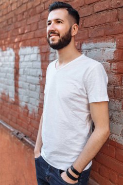 Turuncu tuğla duvara beyaz boş t-shirt şık ve olumlu adam portresi