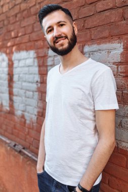 Turuncu tuğla duvara beyaz boş t-shirt şık ve olumlu adam portresi