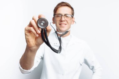 El yakın çekim holding stetoskop, izole beyaz zemin üzerine genç doktor portresi