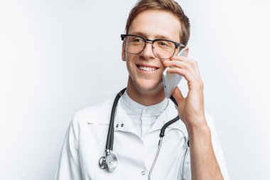 Genç ve yakışıklı doktor hasta ile telefon, stajyer öğrenci klasörle elinde, konuşurken beyaz arka plan,