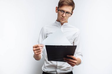 Genç bir portresi beyaz bir arka plan üzerinde beyaz gömlekli gözlüklü çekici adam ellerini ve ona, bakarken bir klasörle izole,