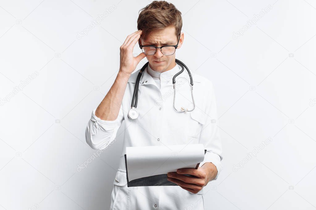 Thoughtful doctor, looking at the documents, and makes notes in the documents, a young student with a folder in his hands, on a white background,