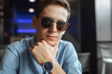 Yakışıklı bir genç adam, Gözlük, bir kafede otururken de ciddi bir göz ile poz hipster portresi,