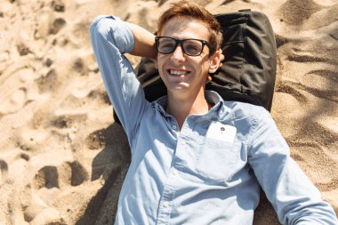 Poz, Genç adam gözlüklü, tatilde çalışmak kum, sahilde yatan,